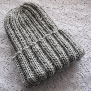 May include: A grey knitted beanie hat with a ribbed texture.
