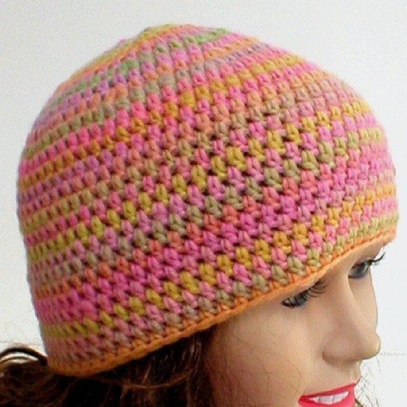 May include: A crocheted hat in shades of pink, orange, yellow, and green. The hat has a simple design and is made with a soft yarn.