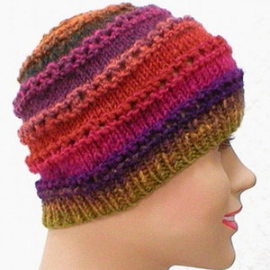 May include: A colorful knitted hat with a striped pattern in shades of red, orange, purple, and green. The hat is made with a textured stitch that creates a unique look.
