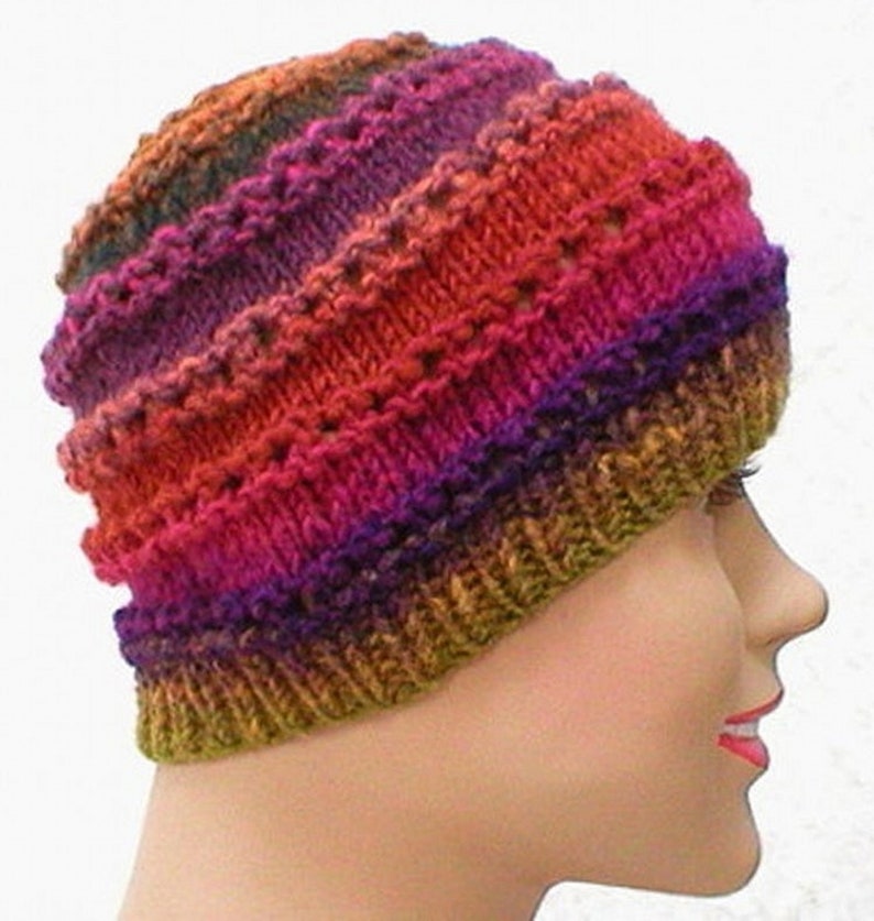 May include: A colorful knitted hat with a striped pattern in shades of red, orange, purple, and green. The hat is made with a textured stitch that creates a unique look.