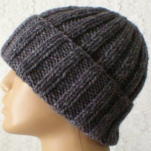May include: A dark grey knitted beanie hat with a ribbed texture. The hat is made of wool and has a simple design.