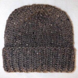 May include: A dark grey knitted beanie hat with a folded-up brim. The hat is made from a thick, textured yarn with white flecks. A classic winter accessory, perfect for keeping warm.