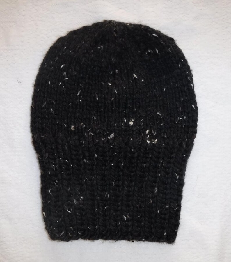 Puede incluir: Un gorro negro tejido con motas blancas. El gorro est&aacute; hecho de un hilo grueso y texturizado y tiene un borde acanalado. El gorro es un estilo cl&aacute;sico, adecuado para el clima fr&iacute;o.