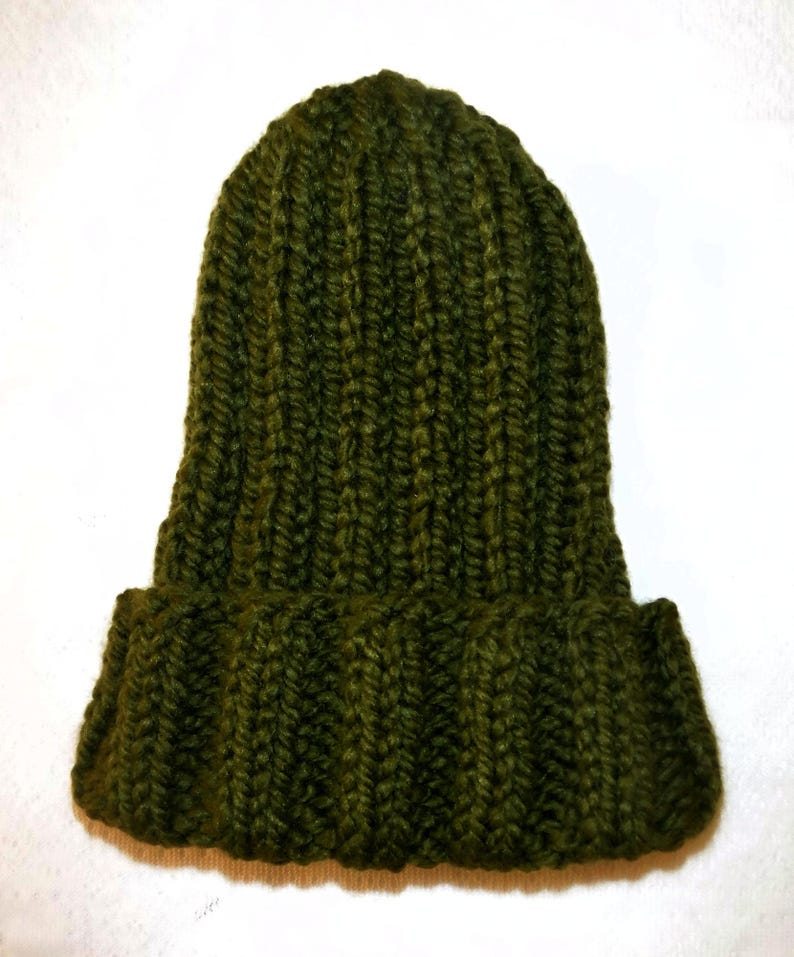 Op de afbeelding: Een donker olijfgroene gebreide beanie met een omgeslagen rand. De hoed is gemaakt van een dik, getextureerd garen en heeft een geribbeld patroon. De hoed wordt getoond tegen een witte achtergrond.