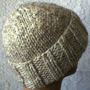 May include: A beige knitted hat with a unique stitch pattern. The hat has a slouchy fit and is made with a soft, textured yarn.