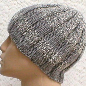 May include: A gray knitted beanie with a cable knit pattern. The beanie is made of a soft, warm yarn and has a slouchy fit.
