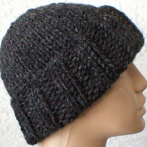 May include: A dark grey knitted beanie hat with a slouchy fit. The hat is made from a thick, textured yarn.