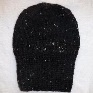 Puede incluir: Un gorro negro tejido con motas blancas. El gorro tiene un borde acanalado y una parte superior redondeada. El hilo parece ser un material grueso y c&aacute;lido, adecuado para el clima fr&iacute;o.