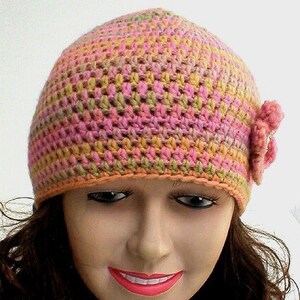 May include: A crocheted hat in shades of pink, orange, and green with a matching flower accent. The hat is made with a textured stitch and has a simple, classic design.