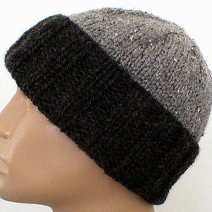 May include: A grey and black knitted beanie hat. The hat has a black band around the bottom and a grey top with a subtle sparkle.