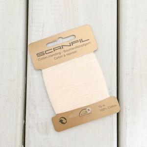 May include: A spool of white cotton mending thread on a gold card with the text "SCANFIL Cotton mending - Baumwollstopfgarn Coton à repriser" and "15 m 100% Cotton".