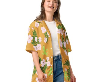 May include: Mustard yellow button-down shirt with a floral and cartoon frog print. The shirt features short sleeves and a white undershirt. The floral pattern includes white and pink flowers with green leaves.