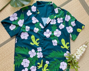 May include: A teal blue short-sleeved button-up shirt with a tropical print featuring green leaves, white flowers, and yellow cartoon characters.