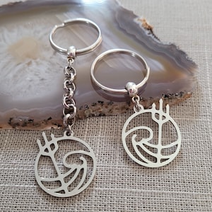 May include: Two silver keychains with a wave and trident design. The keychains are attached to silver key rings.