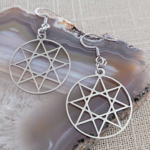 May include: A pair of silver earrings with a geometric star design. The earrings are circular and have a delicate, intricate pattern.