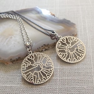 May include: Two silver necklaces with a circular pendant featuring a tree of life design. The pendants are made of metal and have a delicate, intricate pattern.