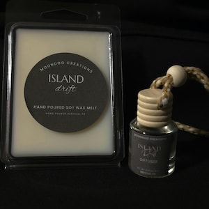 May include: A rectangular plastic container of off-white soy wax melt with a circular black label reading Moondog Creations Island Drift Hand Poured Soy Wax Melt, next to a small glass diffuser bottle with a wooden cap and a hanging rope cord.