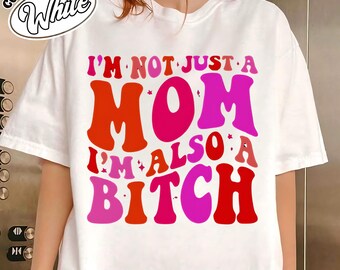May include: White t-shirt with the text "I'M NOT JUST A MOM I'M ALSO A BITCH" in shades of red and pink. The shirt has a crew neck and short sleeves. The words "Comfort Color" and "White" are in a circular design at the top left.