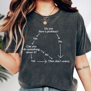 May include: A white ceramic mug with a black handle and the text "But First, Coffee" in a bold, black font. The mug is set against a blurred background, suggesting a cozy setting.