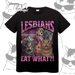 May include: Black t-shirt with the text "LESBIANS" in pink, above a graphic of several cats with surprised expressions. The text "EAT WHAT?!" is below the cats, also in pink.