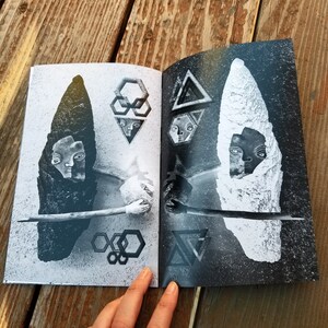 May include: A black and white book with two pages open. The left page features a black and white image of a face with a geometric pattern behind it. The right page features a black and white image of a face with a geometric pattern behind it.