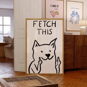 Könnte beinhalten: Ein weißer gerahmter Poster mit einer Schwarzweißillustration eines Hundes, der den Mittelfinger zeigt. Der Poster sagt "FETCH THIS" in schwarzem Text.
