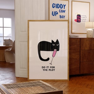 以下が含まれることがあります： 白い背景に「DO IT FOR THE PLOT」というテキストが書かれた、ピンクの飲み物をグラスに入れた黒い猫。