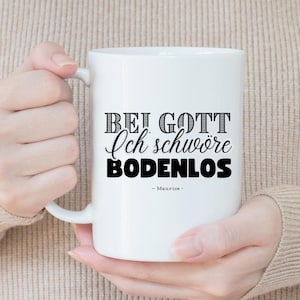 Könnte beinhalten: Weiße Keramiktasse mit schwarzem Text, der "Bei Gott Ich schwöre BODENLOS - Maurice - " lautet.