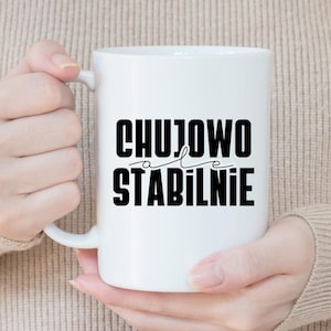 May include: White ceramic mug with black text that reads "CHUJOWO ale STABILNIE".