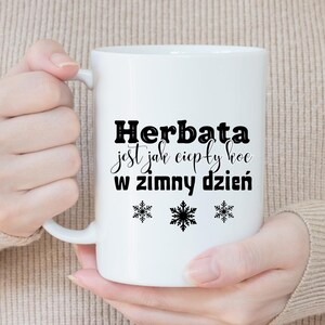 May include: White ceramic mug with a black inscription that reads "Herbata jest jak ciepły koc w zimny dzień" and three black snowflake designs.