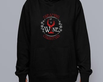 Peut inclure: Sweat à capuche noir avec une poche avant. Le sweat-shirt présente un motif rouge et blanc avec l'inscription "Dreaming of a Wine Christmas", un dessin de verre à vin et des flocons de neige. Le motif est centré sur la poitrine.