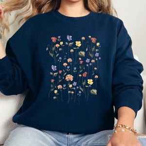 May include: A navy blue sweatshirt with a floral print featuring a variety of colorful flowers and leaves.