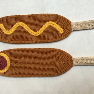 Könnte beinhalten: Zwei gehäkelte Corn Dog Spielzeuge. Eines hat ein gelbes Senfdesign und das andere ein rotes und gelbes Hot Dog Design.