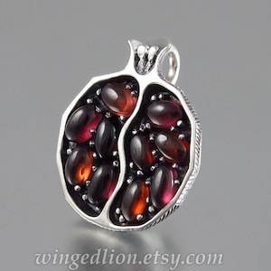 May include: A silver pendant shaped like a pomegranate, with red and black gemstones set into the design.