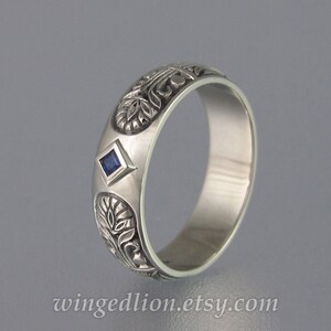 May include: A silver band ring with an intricate floral design and a small, square, blue sapphire gemstone.