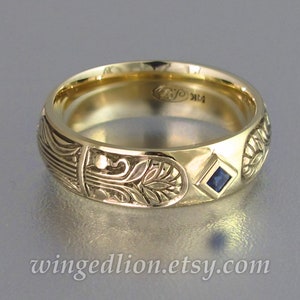 May include: A gold band with an intricate floral design and a small blue sapphire gemstone. The band is engraved with the initials "R" and "K".