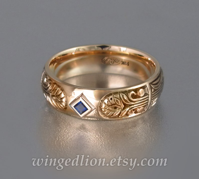 May include: A gold band ring with intricate carvings and a small blue sapphire gemstone. The ring is engraved with the text "RJC 14K".