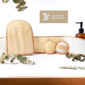 May include: A set of four natural loofah bath products, including a loofah mitt, a loofah headband, and two loofah scrubbers. The products are arranged on a white surface with a sprig of eucalyptus leaves. The text "LOOFAH CRAFTS" is visible in the top right corner of the image.