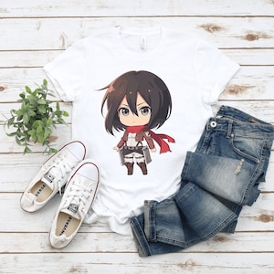 May include: White t-shirt with a cartoon illustration of a female anime character with brown hair, wearing a brown jacket and red scarf. The character is holding a sword and has a determined expression.
