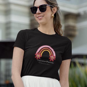 May include: A black t-shirt with a rainbow and flowers graphic. The text "Talento + Pasion:  Alcanzar" is printed on the shirt.