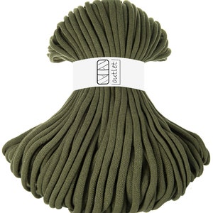 May include: A large spool of dark green cotton cord, wrapped in a circle. The cord is thick and has a rough texture. A white label with the text "outlet" is attached to the spool.