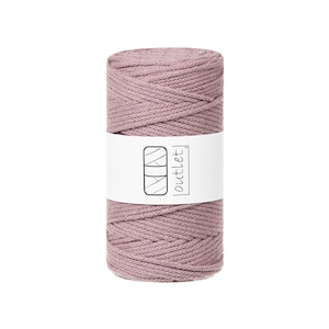 Pode incluir: Um carretel cilíndrico de fio de macramé rosa empoeirado. Uma etiqueta branca com um gráfico preto e a palavra "outlet" está enrolada ao redor do centro. O fio é bem enrolado, mostrando a textura do material.