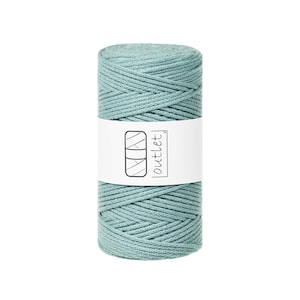 May include: A teal macrame cord spool. The cord is wound into a cylindrical shape. A white label with the word "outlet" and a logo is wrapped around the centre of the spool.