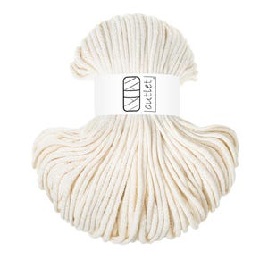 Può includere: Una matassa di corda di cotone spessa e ritorta color bianco sporco, avvolta in una fascia di carta bianca. La fascia presenta un logo grafico nero composto da due rettangoli sovrapposti e il testo "outlet" in un carattere nero.