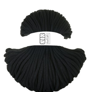Può includere: Un grande rotolo di cordoncino di cotone nero, perfetto per progetti di artigianato. Il cordoncino è avvolto strettamente e ha una texture liscia. L'etichetta sul rotolo recita "outlet".