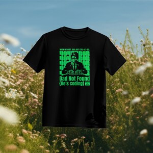 Puede incluir: Camiseta negra con un gráfico verde de una persona sentada frente a una computadora. El texto en la camiseta dice "When in doubt, Dad just Ctrl-Alt-Del. Dad Not Found (He's coding)"