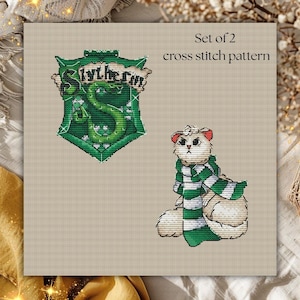 May include: A cross-stitch pattern set featuring two designs. One is the Slytherin crest in green and white. The other is a white cat wearing a green and white striped scarf. The text "Set of 2 cross stitch pattern" is at the top.