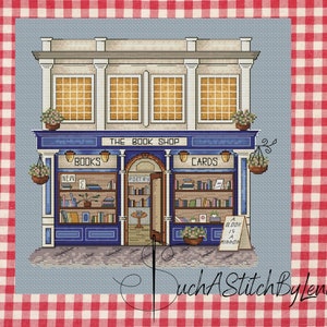 Pode incluir: Padr&atilde;o de ponto cruz de uma livraria pitoresca com uma fachada azul e branca, rotulada como "The Book Shop". A loja apresenta prateleiras de livros, cestos de flores suspensos e as palavras "Books" e "Cards". Uma placa diz "A Book is a Mirror."