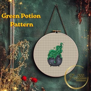 May include: A cross-stitch pattern of a bubbling green potion in a black cauldron, displayed in a round embroidery hoop. The text "Green Potion Pattern" is above the hoop. The background is a dark green wall with decorative elements.