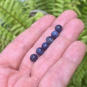 May include: A row of six round, blue, and white gemstone beads.